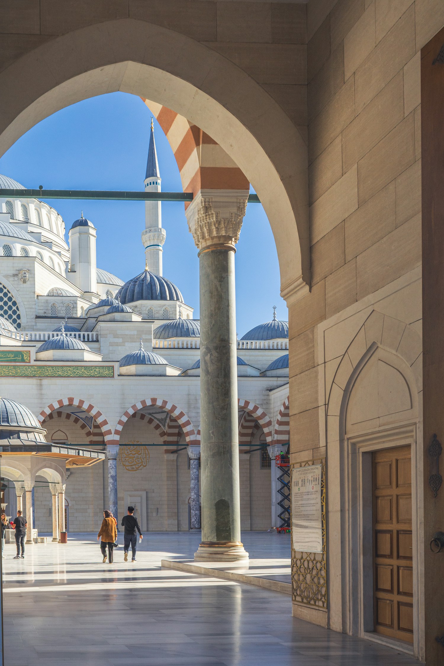 Visitors walking through the sunlit courtyard of a mosque in Istanbul
