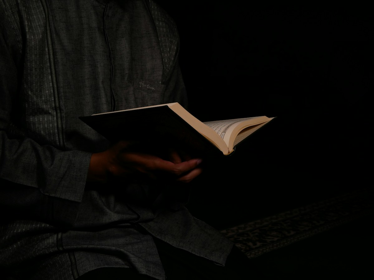 A reader holding an open Qur’an in a quiet room